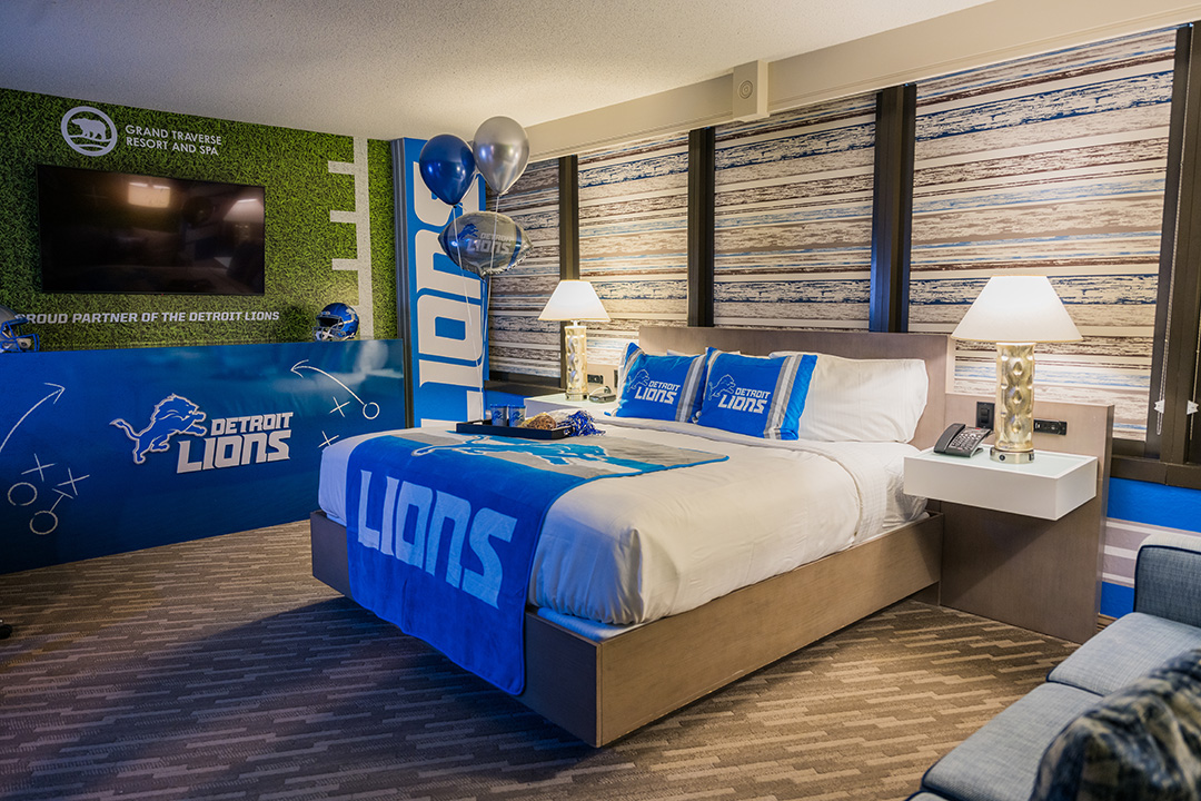 Detroit Lions-themed hotel room featuring team logos, blue and silver decor, branded bedding, balloons, and a football-inspired wall design.